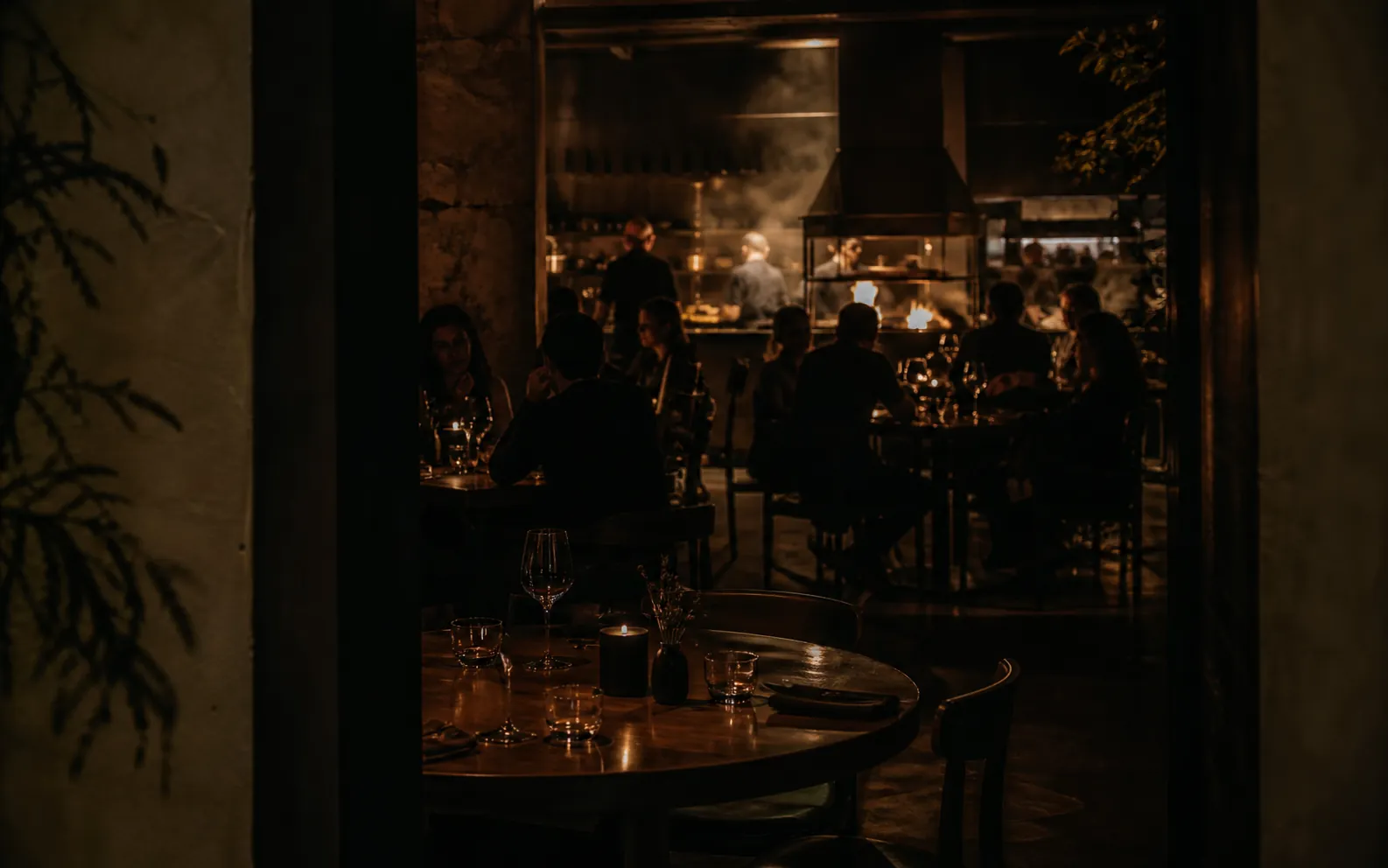 EMBER's dining room in the evening — guests, candles and an open kitchen